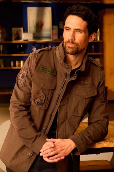 Chaqueta estilo militar color caqui con múltiples bolsillos y cuello alto.