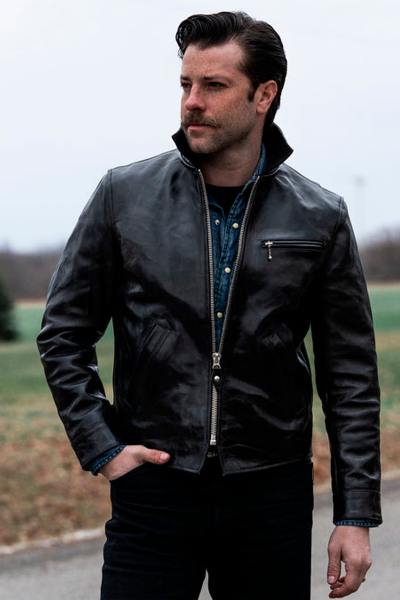 Chaqueta de cuero negro brillante con cuello de camisa.